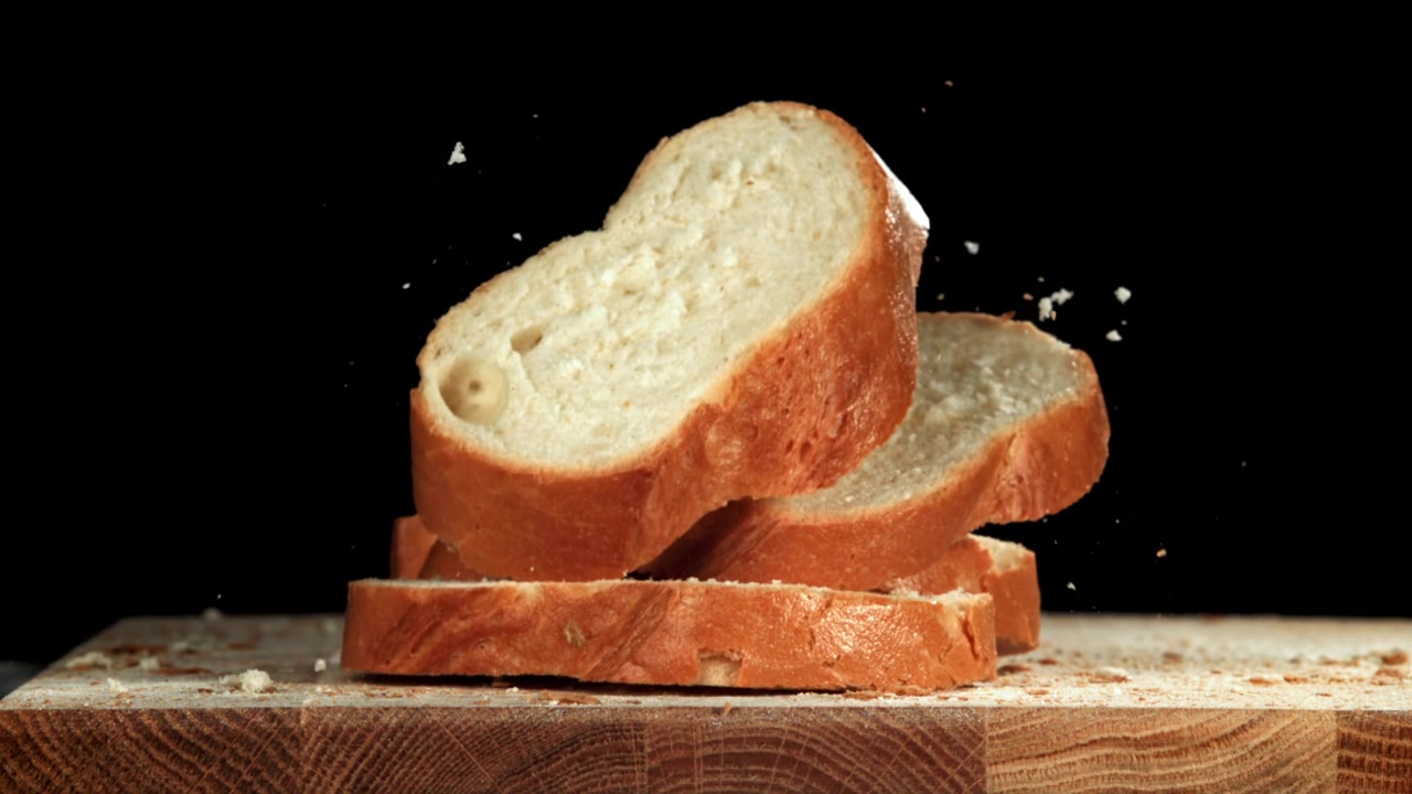 Slow Motion of Fresh Bread Slices Falling onto a Wooden Board