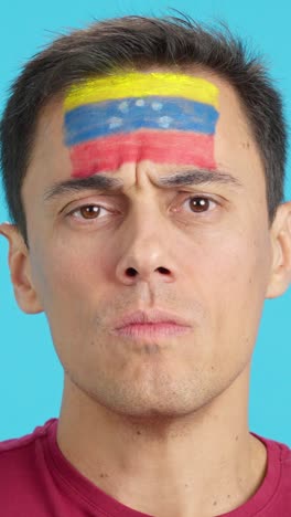 serious man with a venezuelan flag painted on the face