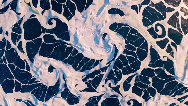 Aerial view of ocean waves creating intricate patterns. The video captures the dynamic movement