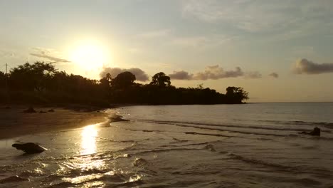 Aerial-fly-back-shot-on-sunset-beach,-São-Tomé-Island