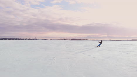 un atleta masculino con ropa deportiva está haciendo kitesurf en la nieve en un hermoso paisaje invernal.