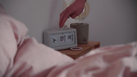 hand is changing white retro flip clock calendar date and day next to the bed in the morning