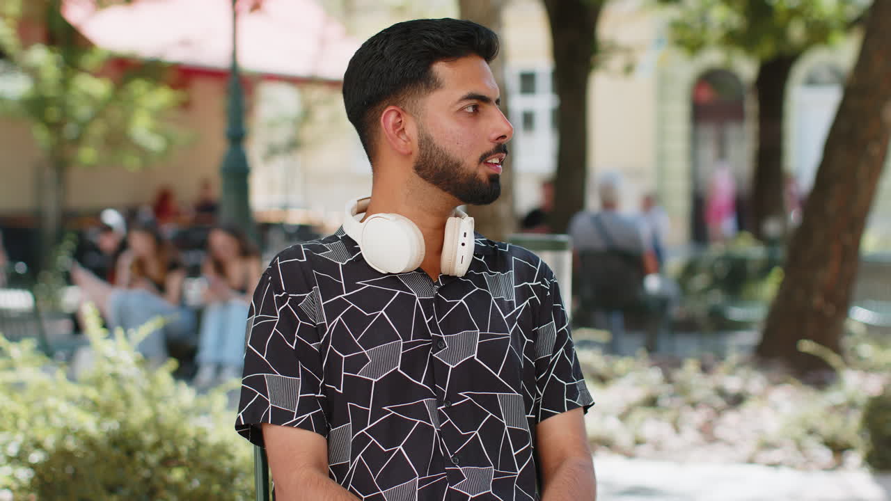 Happy young indian man tourist showing thumbs up like positive sign good feedback on city street