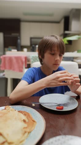 boy eating pancakes with strawberry