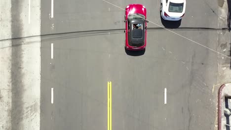 Der-Rote-Mini-Cooper-Fährt-Ins-Bild-Und-Die-Kamera-Folgt-Sanften-Luftaufnahmen,-Drohnenaufnahmen-Aus-Der-Vogelperspektive-In-La-At-Venice-Beach,-USA,-2018