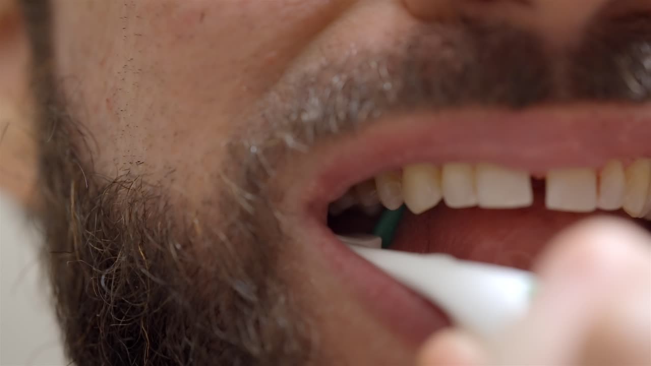 Close-up of a man's mouth using an interdental cleaning brush