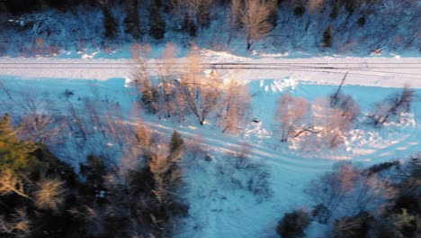 aerial top down slide over a snow covered set of railroad tracks running through a winter forest