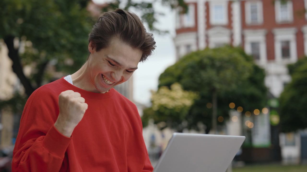 Uomo che usa un laptop all'aperto in un ambiente urbano