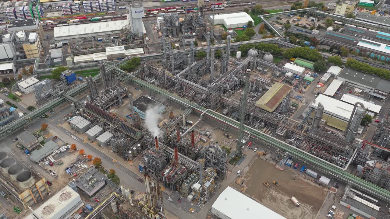 Tomada Aérea em Ângulo Elevado Revelando uma Extensa Refinaria de Petróleo e Fábrica Química, com Fumaça Saindo de sua Complexa Rede de Tubulações e Torres