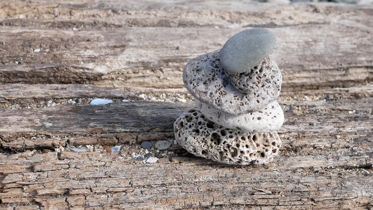 Small textured beach rocks balanced zen like on wooden beach sleeper