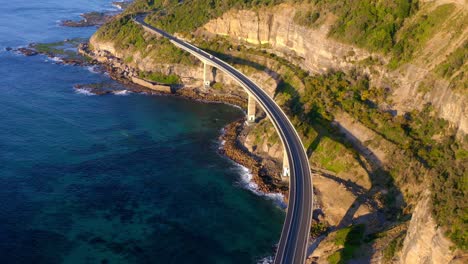 view of iconic sea cliff bridge with cars driving on sunny day in new south wales, australia