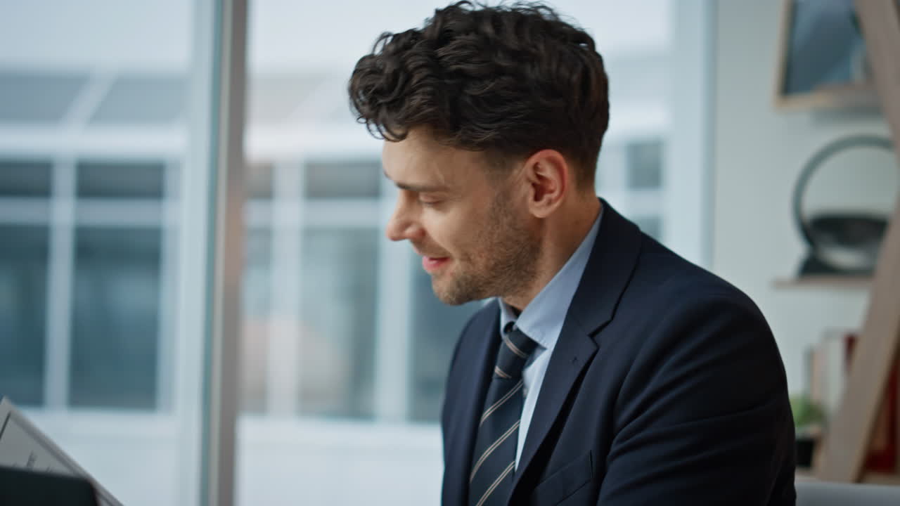 Cheerful entrepreneur looking documents after laptop typing in office closeup