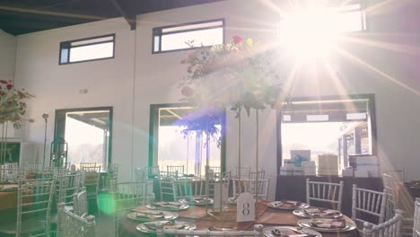 smooth pull-out from a floral centerpiece close-up to reveal an elegant reception table, bathed in warm sunlight and showcasing beautiful sunflare details.
