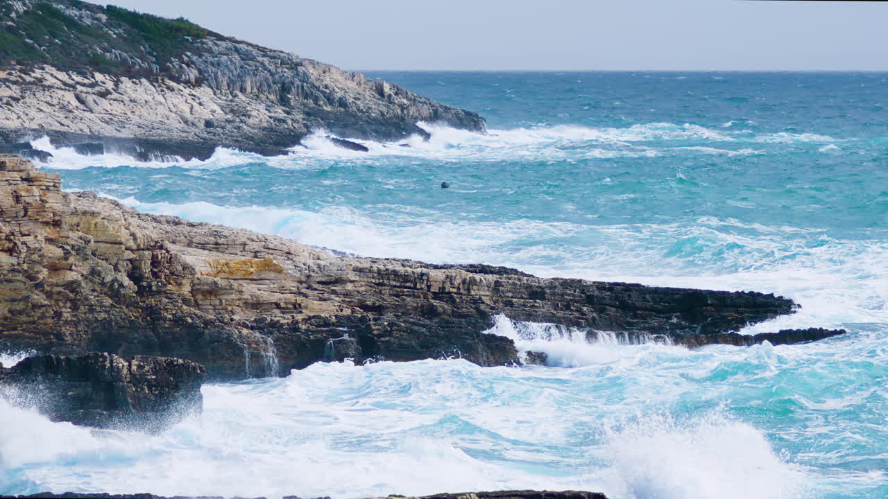 grandes olas rompiendo en la costa rocosa, mar inquieto en clima tormentoso y ventoso