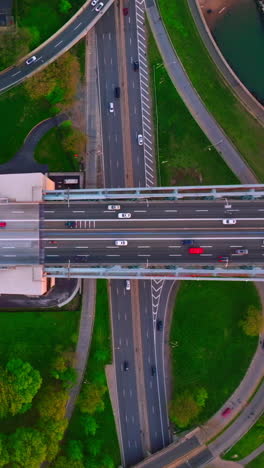 motorways crossing each other and green park area. cars running quickly over the roads in big city. vertical video