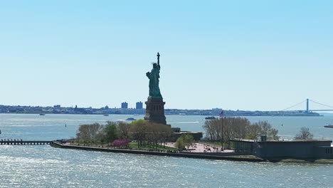 aerial zoom shot showing famous statue of liberty during sunny day in new york city