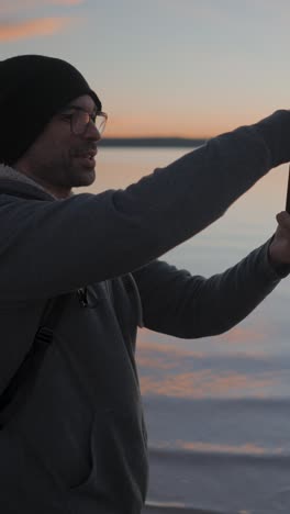 man taking photos of a beautiful sunset over water