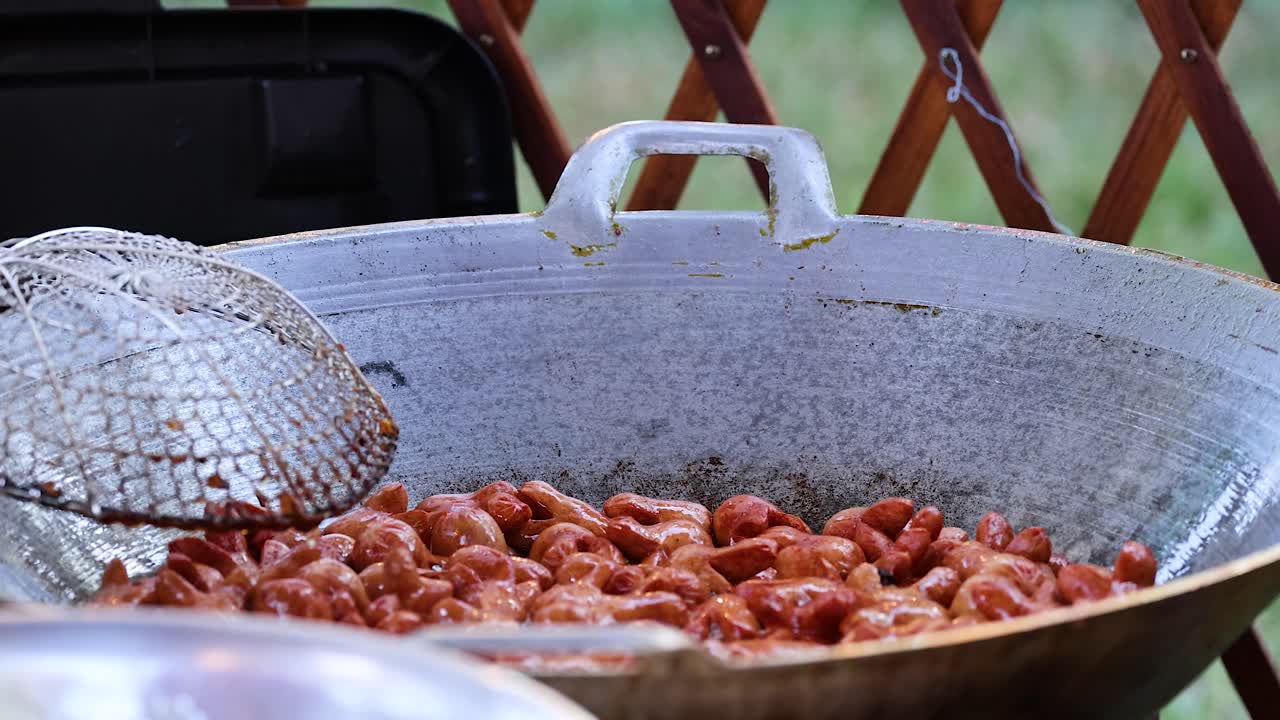 salchichas fritas en una sartén grande al aire libre