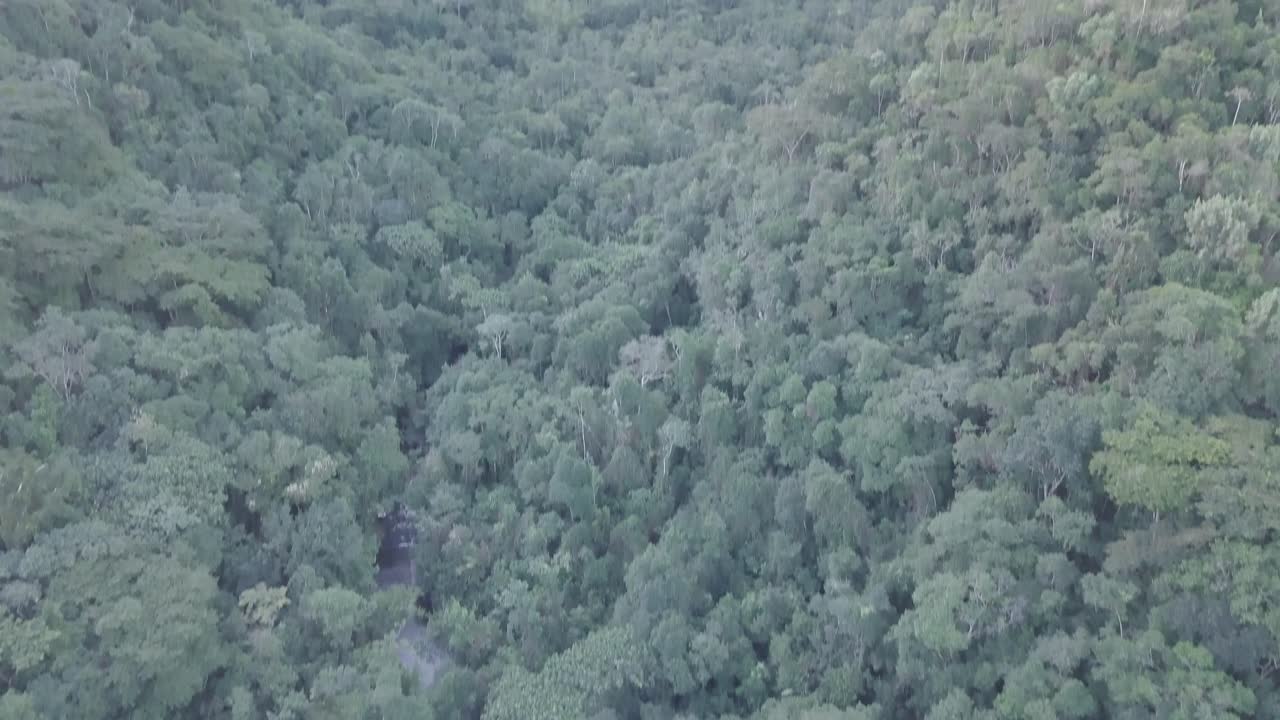 Slow pan above Brazilian waterfall in Amazon rainforest to reveal sunset over mountain