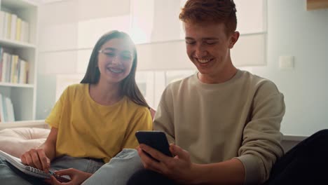 Two-caucasian-teenage-friends-having-fun-while-using-mobile-phones-in-bedroom