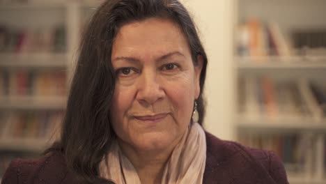 Portrait-shot-of-middle-aged-woman-looking-at-camera-inside-library,close-up