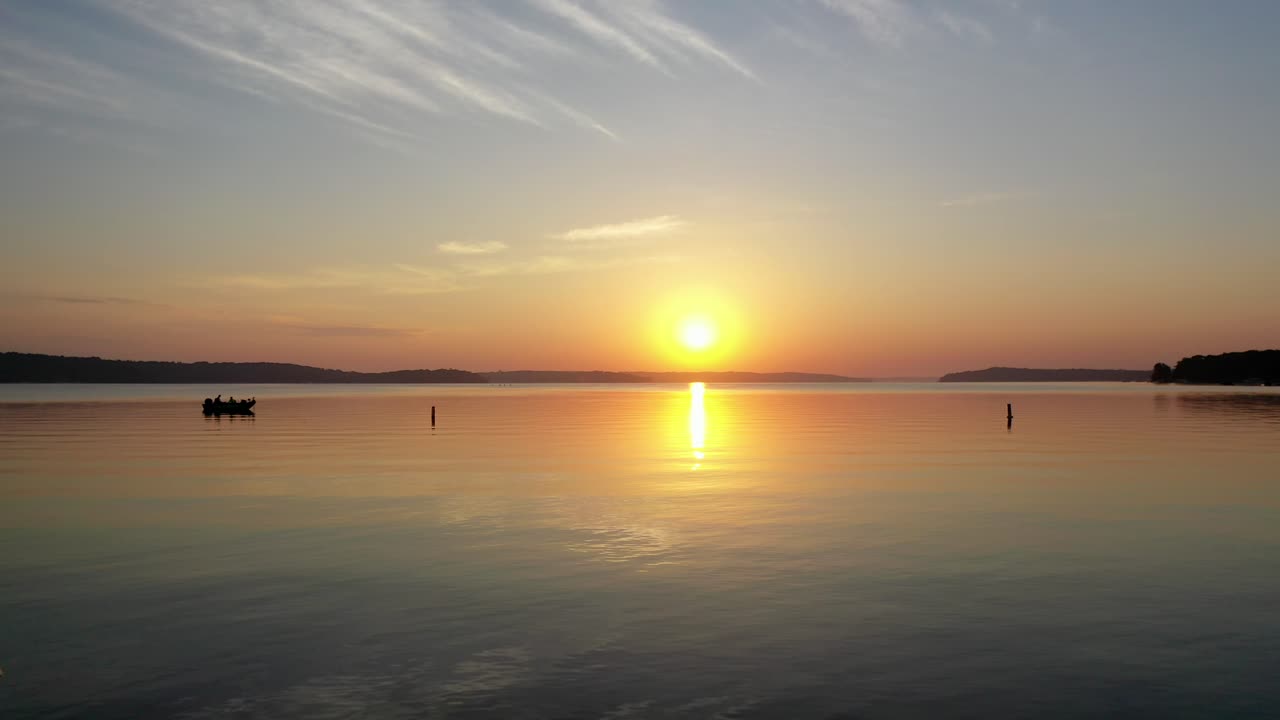 hermosa toma de drones desnatados de navegantes pescando durante la hora dorada con la puesta de sol sobre el lago de ginebra, wisconsin