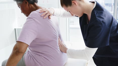 Diverse-female-doctor-testing-back-of-senior-female-patient-in-hospital,-slow-motion