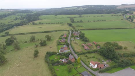 moving and panning drone footage showing a small countryside village, farm and surrounding fields and landscape in rural yorkshire, england, uk