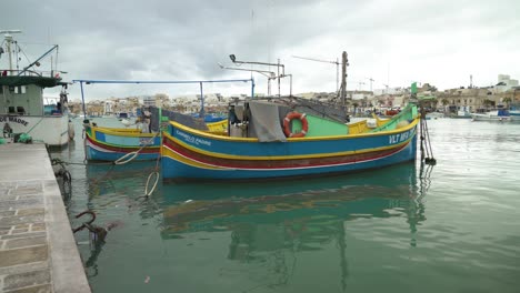 multi-coloured maltese fishing boats rocking on surface of water in marsaxlokk bay in winter