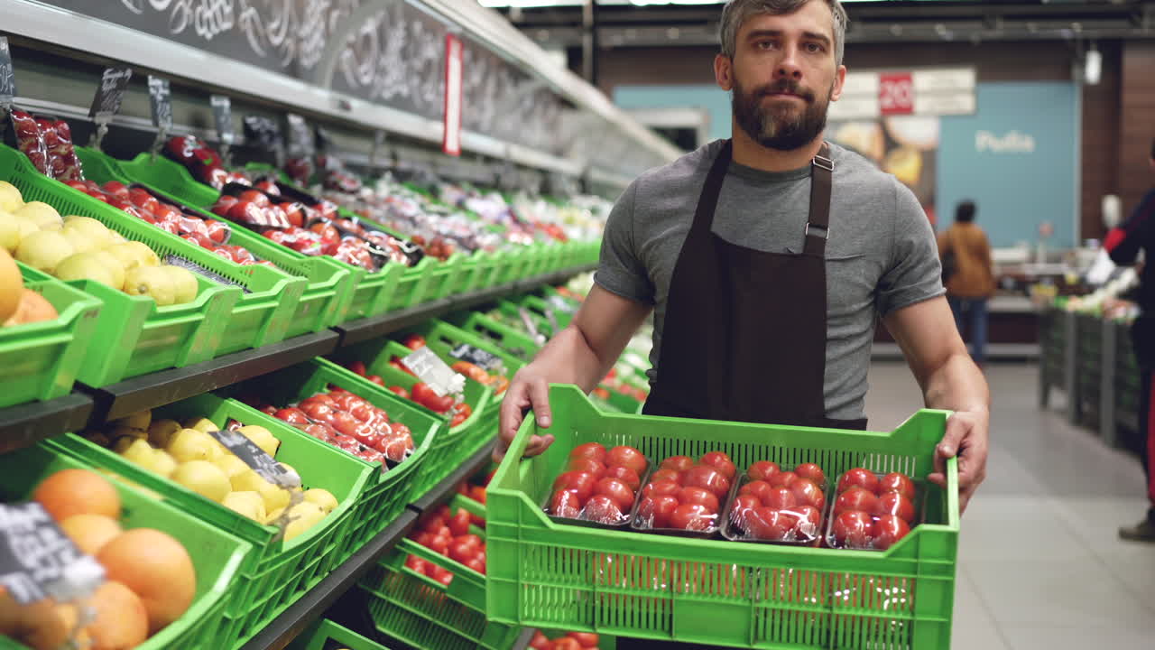 Bir markette domates kasası taşıyan adam.