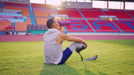 athlete with prosthetic leg resting and drinking in a stadium