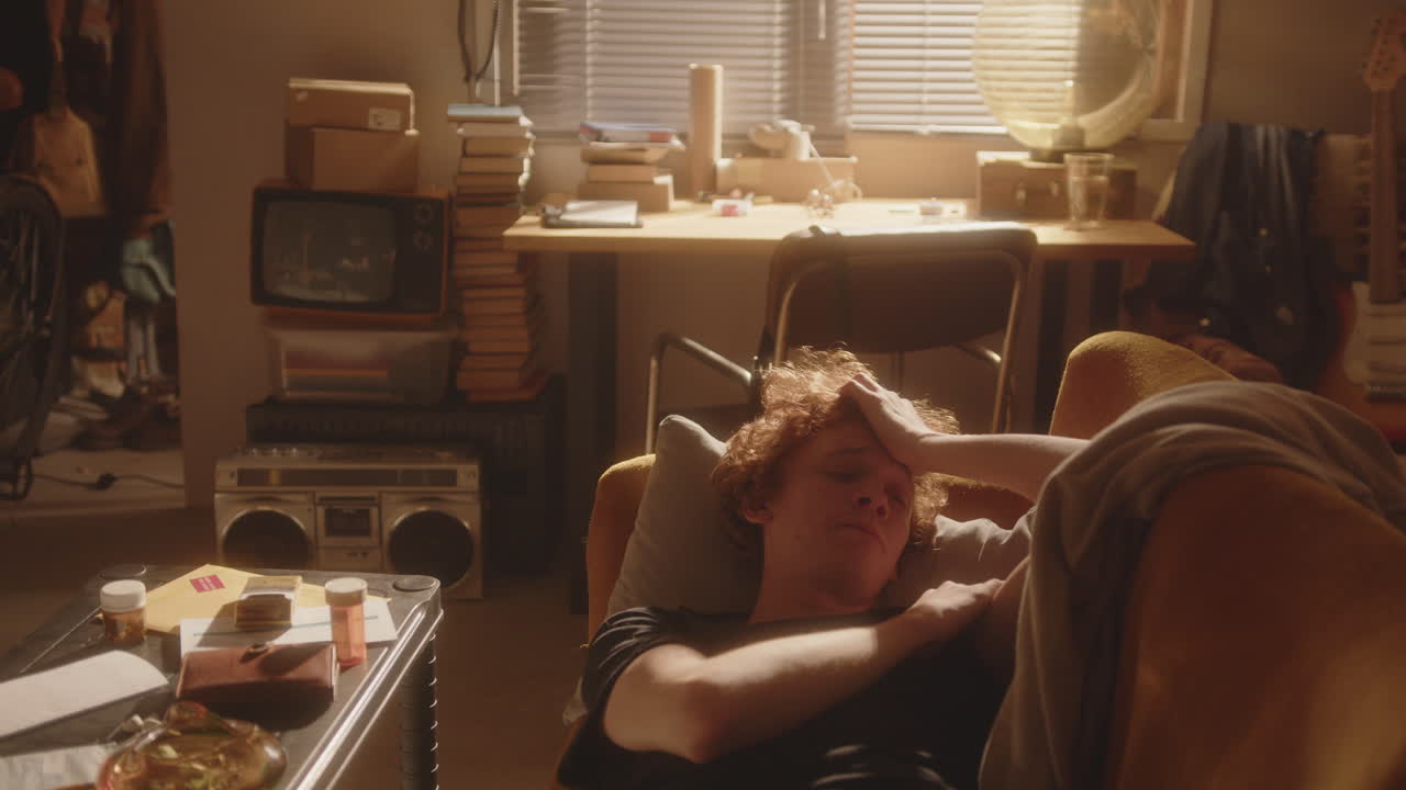 우울증 을 고 있는 감정적 으로 고갈 된 남자 가 비는 방 에서 소파 에 누워 있다