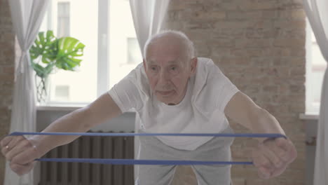 old man using a stretching band and exercising at home 1