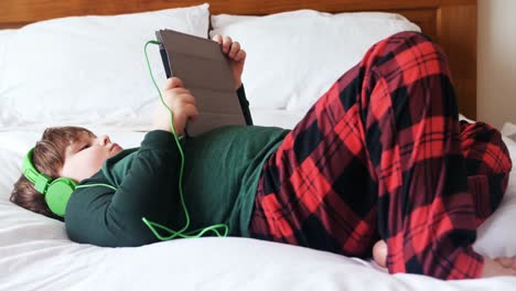boy in headphones using digital tablet in bedroom 4k