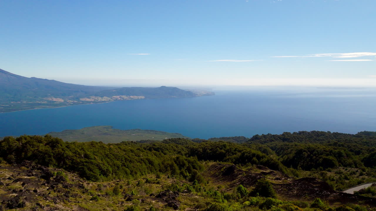 Drone flies past traveler on rocky outcrop on rugged Osorno volcano in Chile