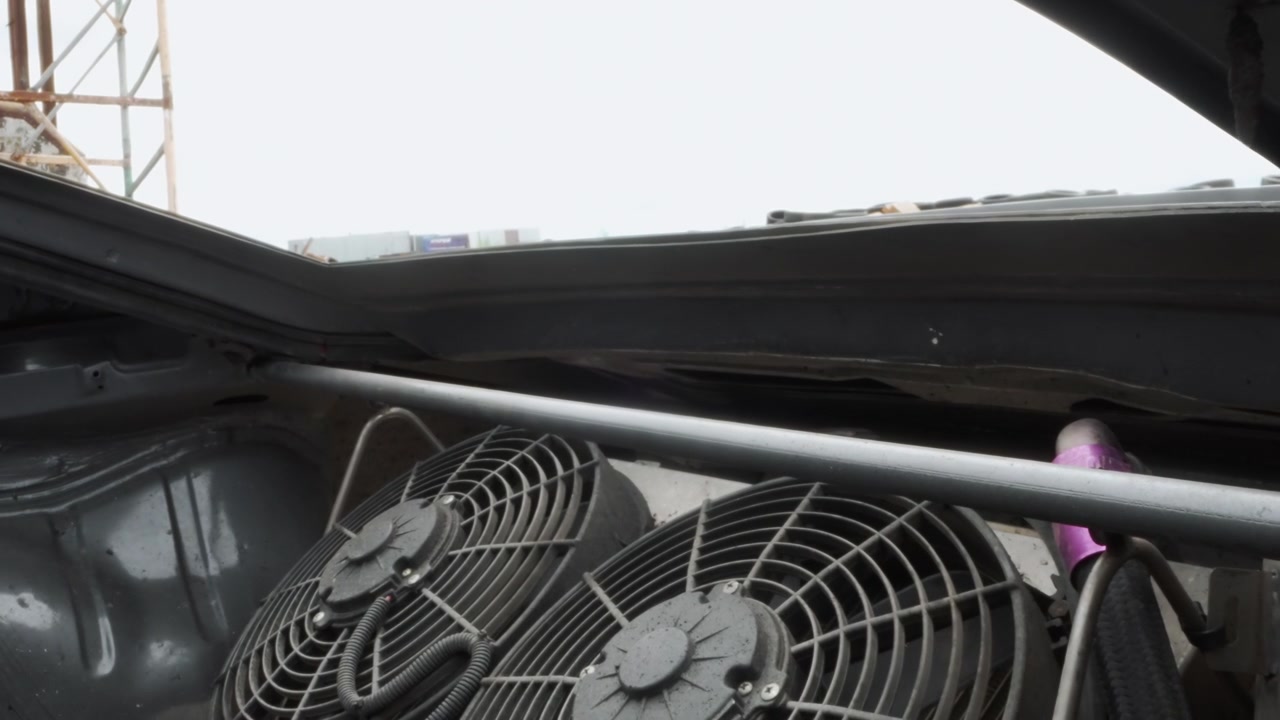 Gros plan des ventilateurs de radiateur de voiture sous un capot ouvert