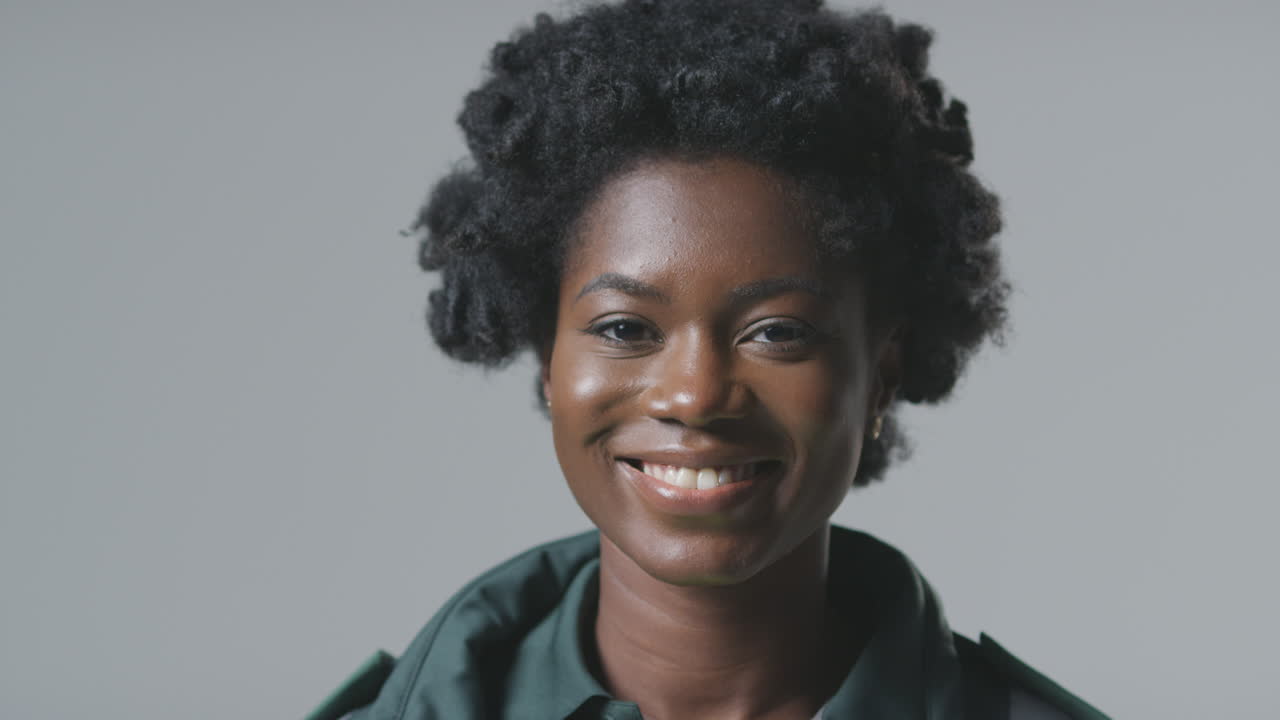 retrato de estudio de una joven paramédica sonriente en uniforme contra un fondo plano