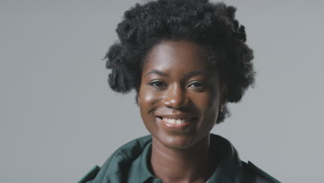 studio portrait of smiling young female paramedic in uniform against plain background
