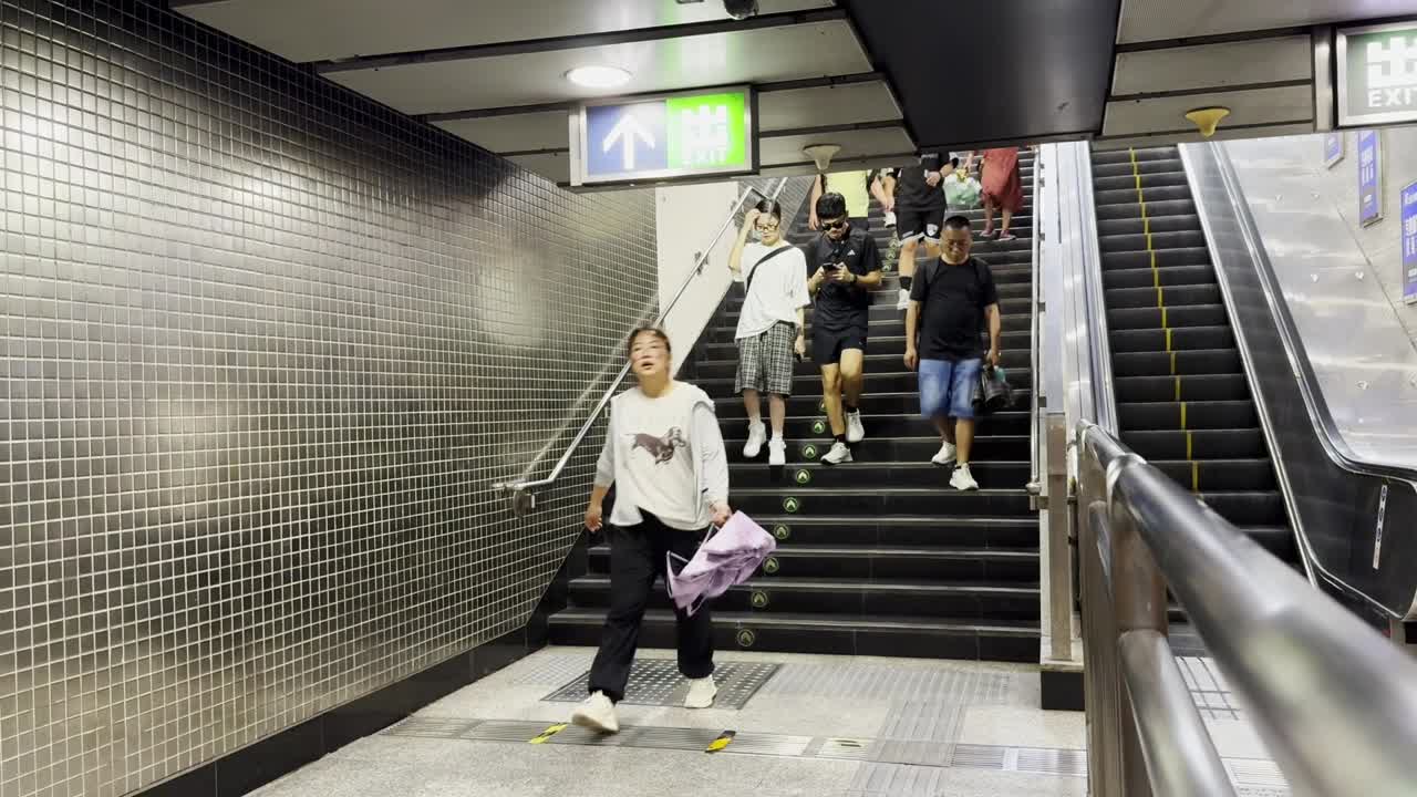 Crowds of people walk down the stairs at a Beijing subway station entrance, eager to catch their trains.