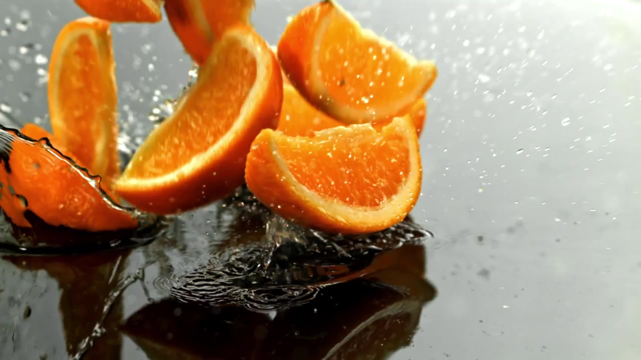 Fette d'arancia vivaci che schizzano in acqua scura al rallentatore.