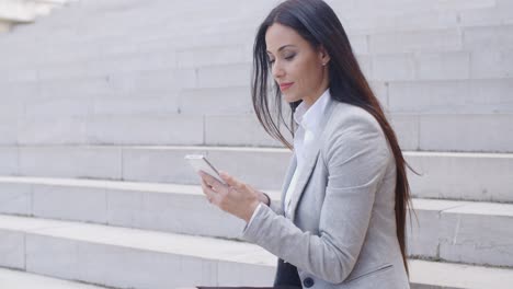 Pretty-young-worker-sitting-on-steps-with-phone