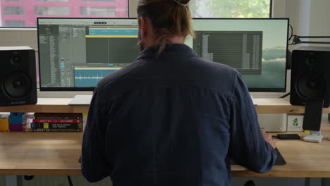 experimentar la productividad moderna con un hombre de cola de caballo inmerso en el trabajo de la computadora en su escritorio
