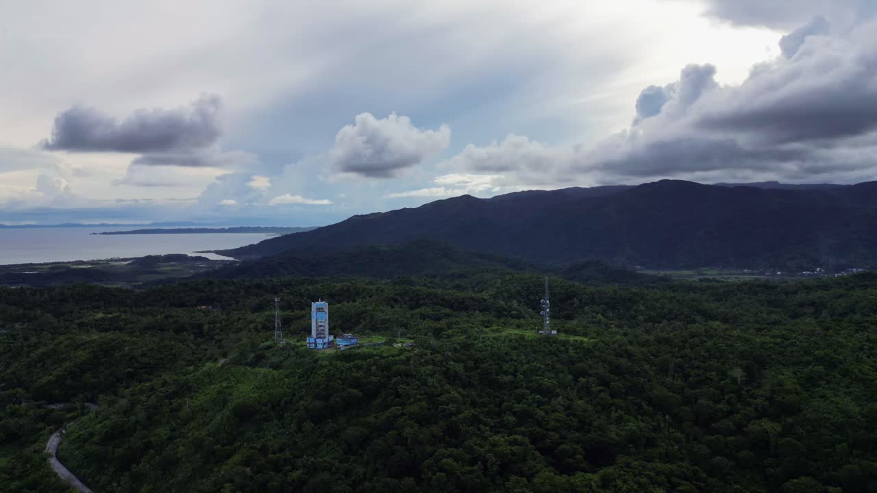 Aerial hyperlapse of stormy clouds forming above PAGASA Weather Radar Station atop lush tropical hills at island of Catanduanes, Philippines