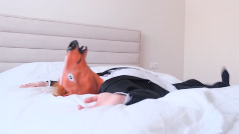 young businessman with the head of a horse lying on a bed in a hotel corporate at work young businessman with the head of a horse lying on a bed in a hotel corporate at work