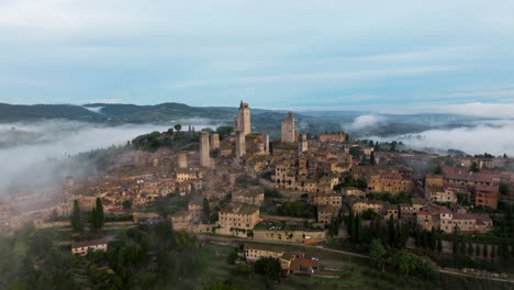 scenic view over foggy landscape in san gimignano, tuscany, italy - aerial drone shot