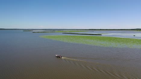 volando sobre un barco solo en el mar, fondo de juncos costeros, avance aéreo