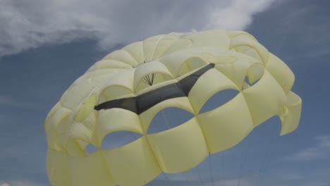 close-up of a parachute flying in wind with blue sky and clouds