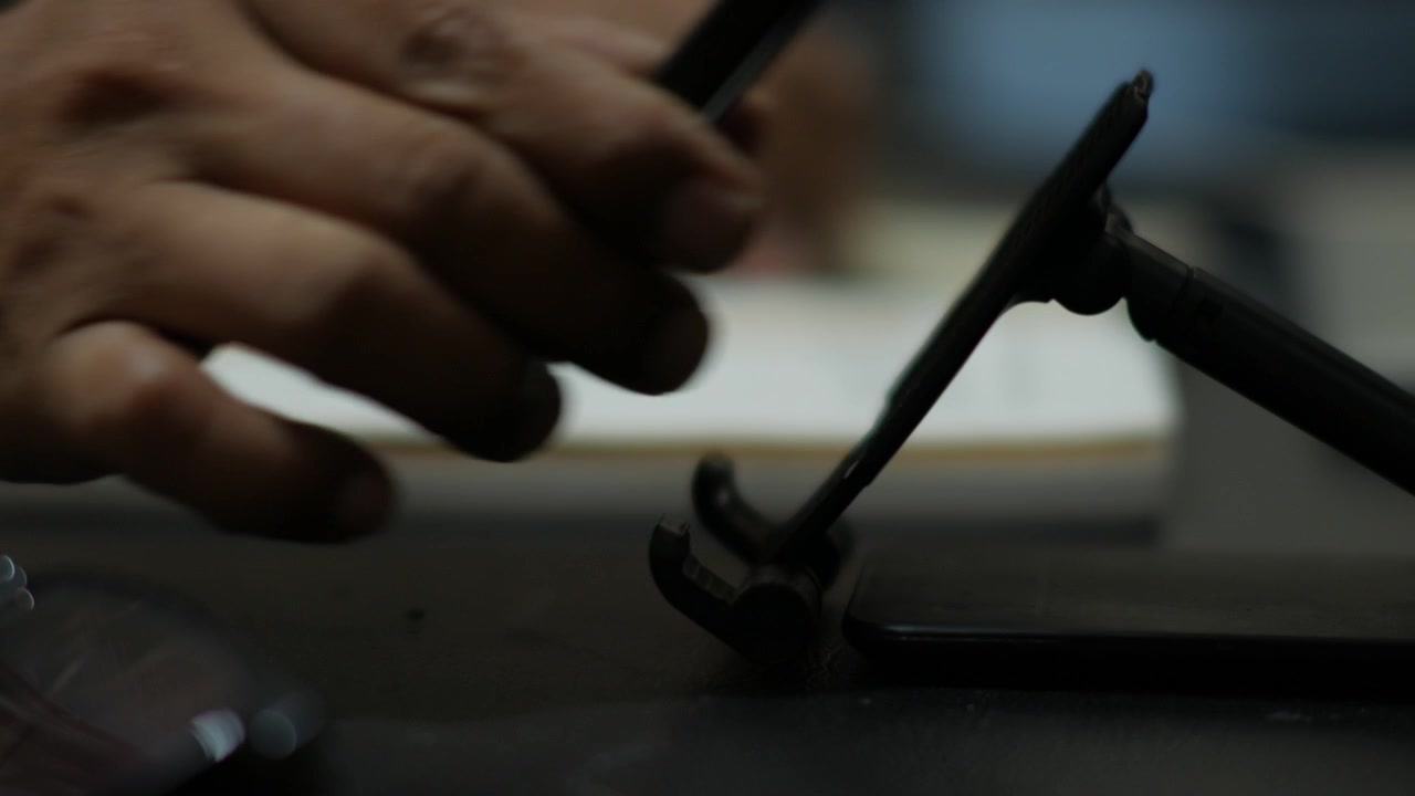 Person Picking Up Smartphone from Desk Stand