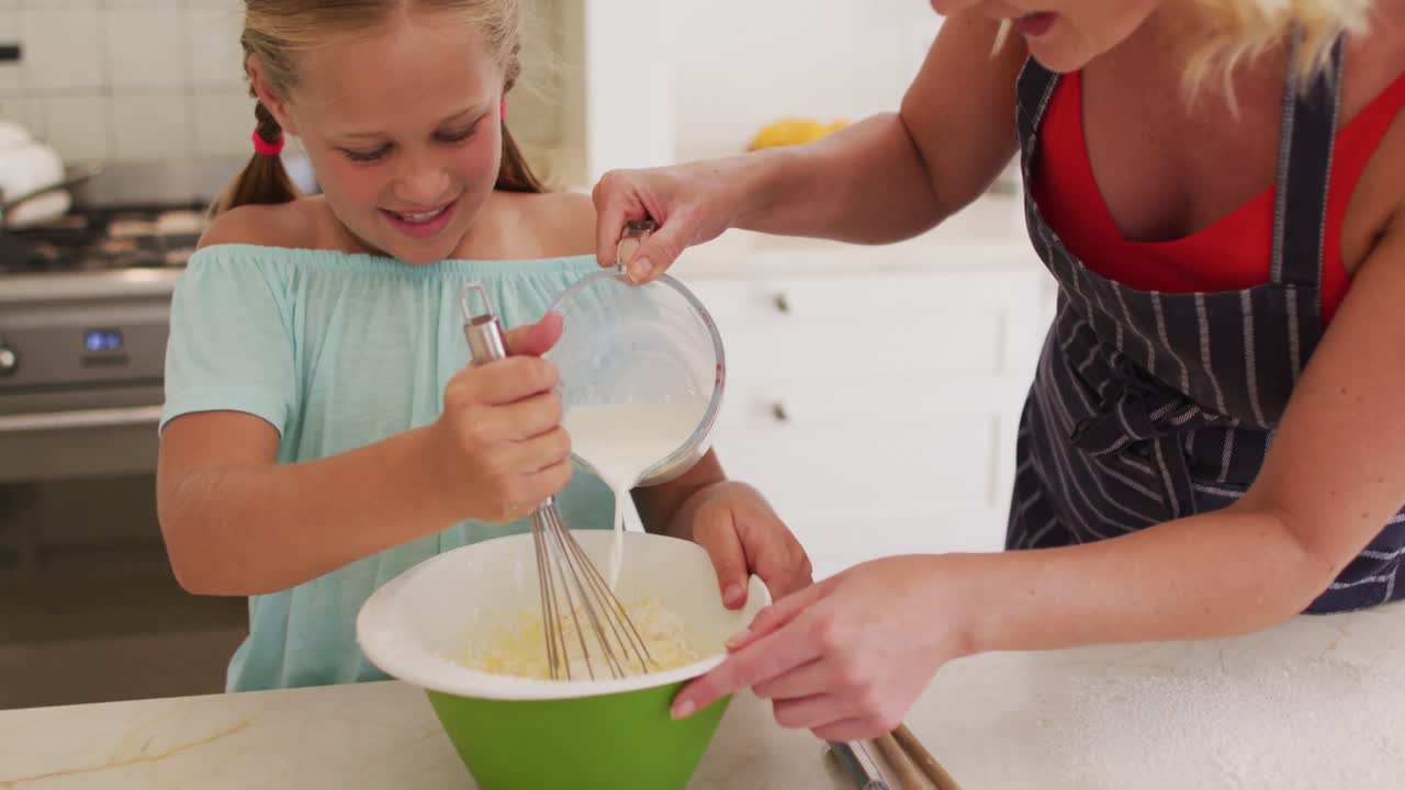 Caucasian mother and daughter baking together in the kitchen at home