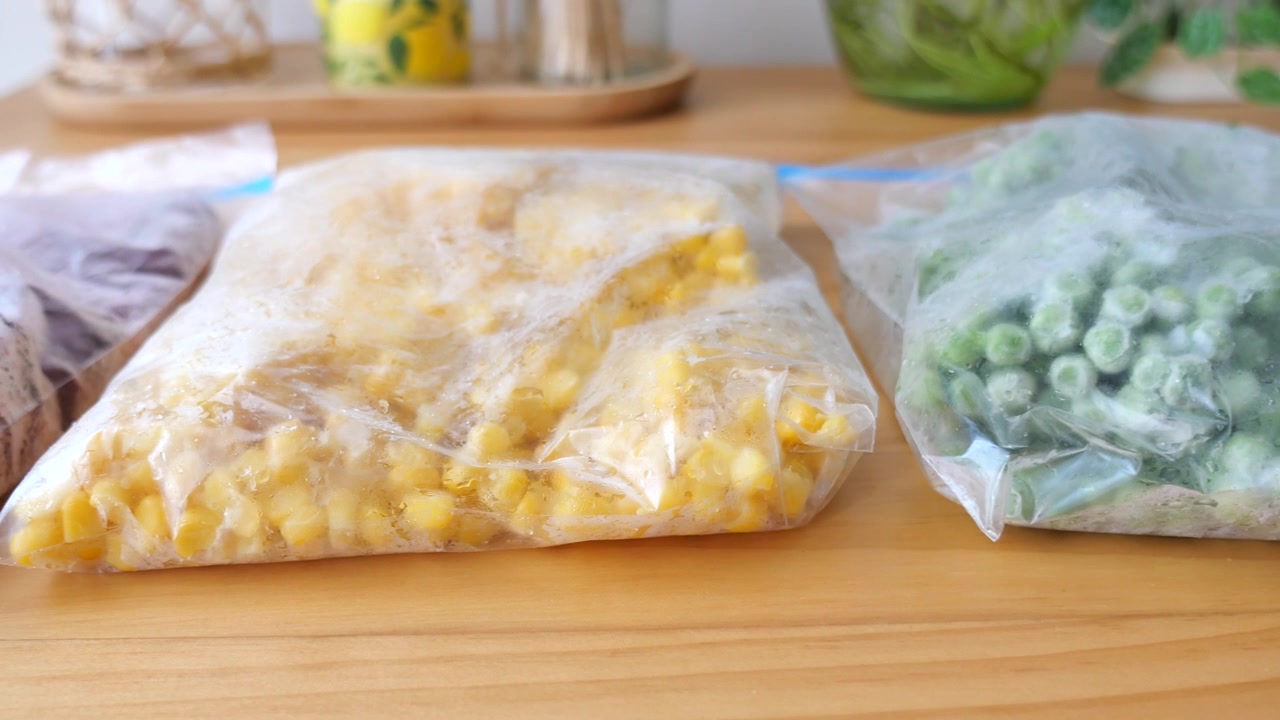 Frozen Vegetables and Berries in Plastic Storage Bags on Wooden Table